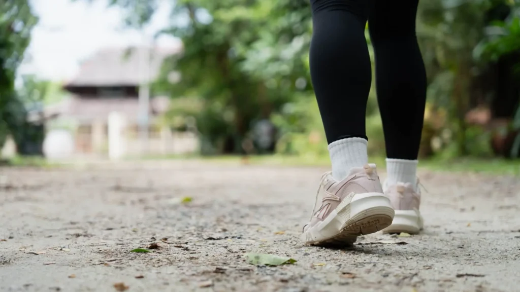 Close-up of a person walking outdoors in running shoes, representing healthy foot movement and alignment.